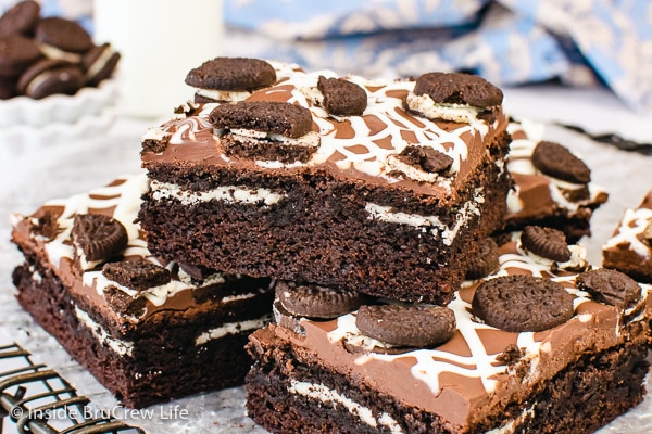 Chocolate brownies with a hidden Oreo cookie and topped with chocolate stacked on a wire rack.