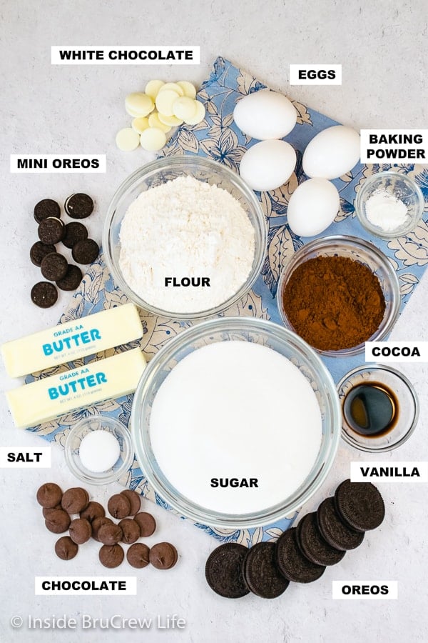 An overhead picture of a white board with bowls of ingredients needed to make brownies stuffed with Oreos.