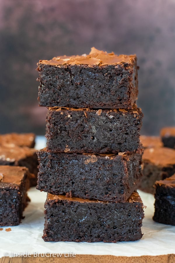 A stack of four fudge brownies on a board.