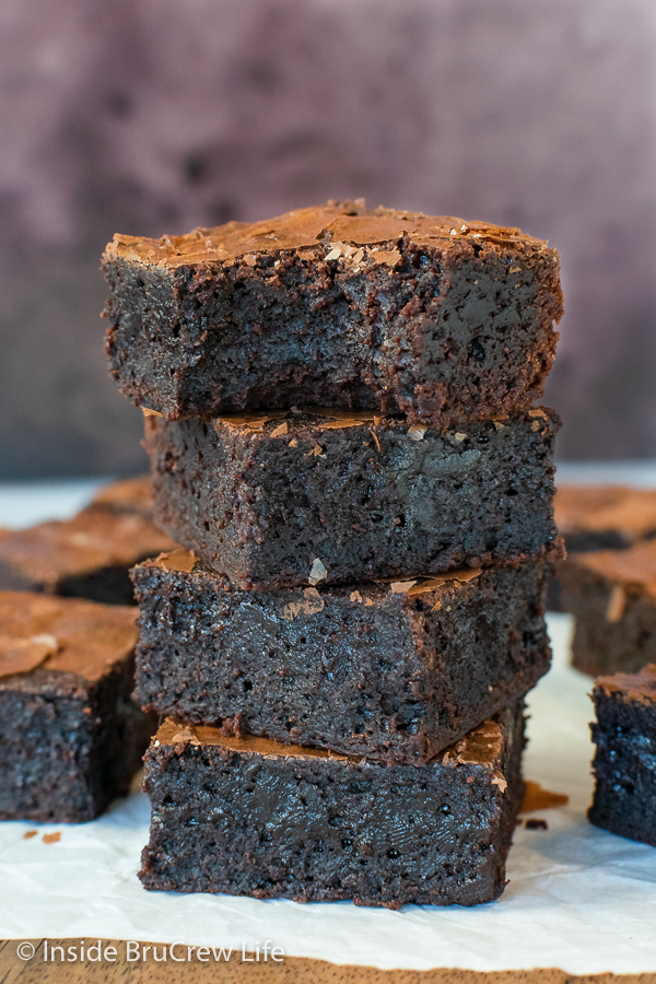 A stack of four fudgy brownies with a bite out of the top one.