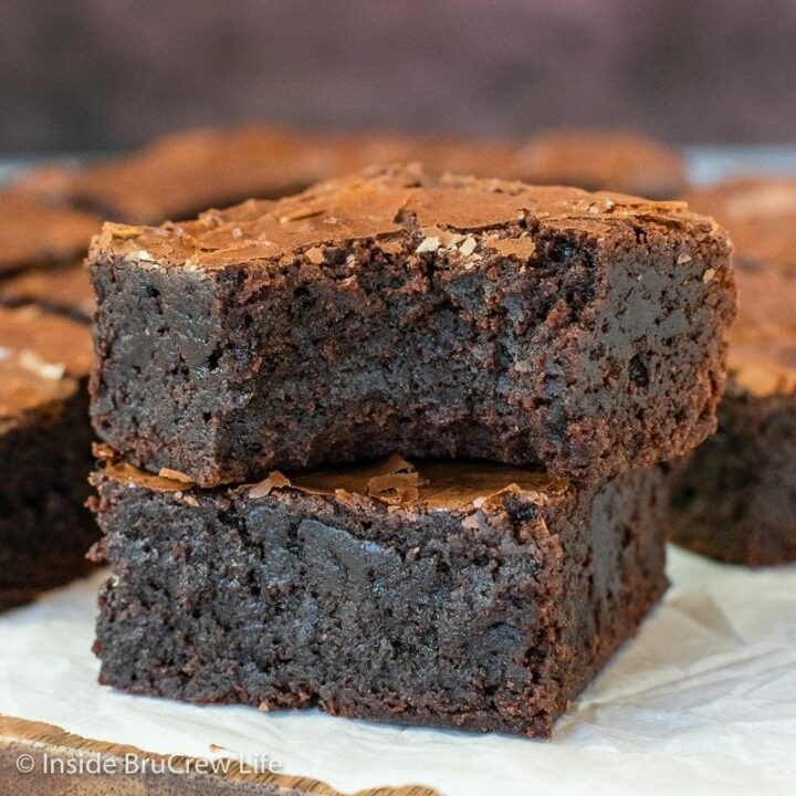 Two chocolate brownies stacked on top of each other with a bite out of one.