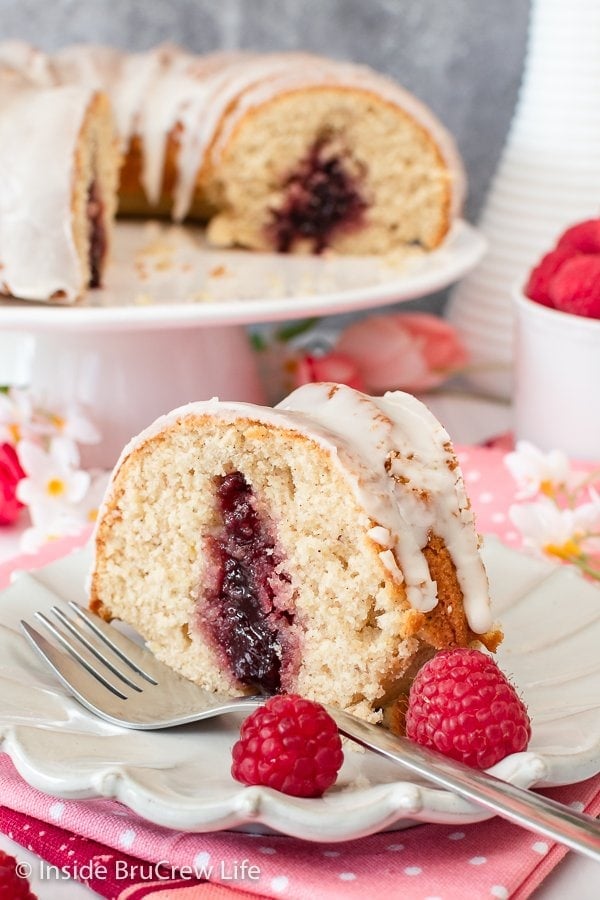 A slice of bundt cake on a white plate with a fork and berries.