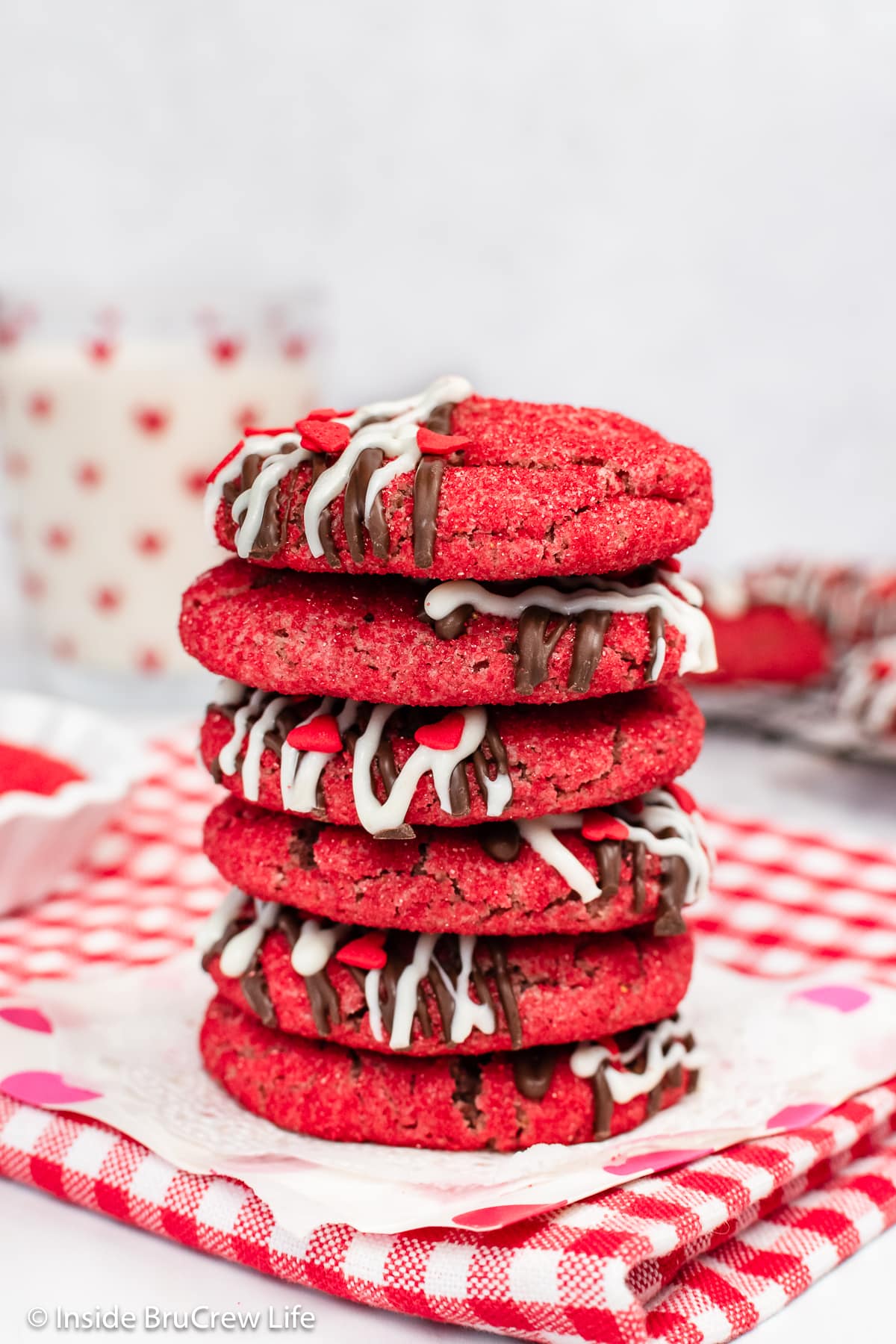 A stack of red cookies on a red and white checkered towel.
