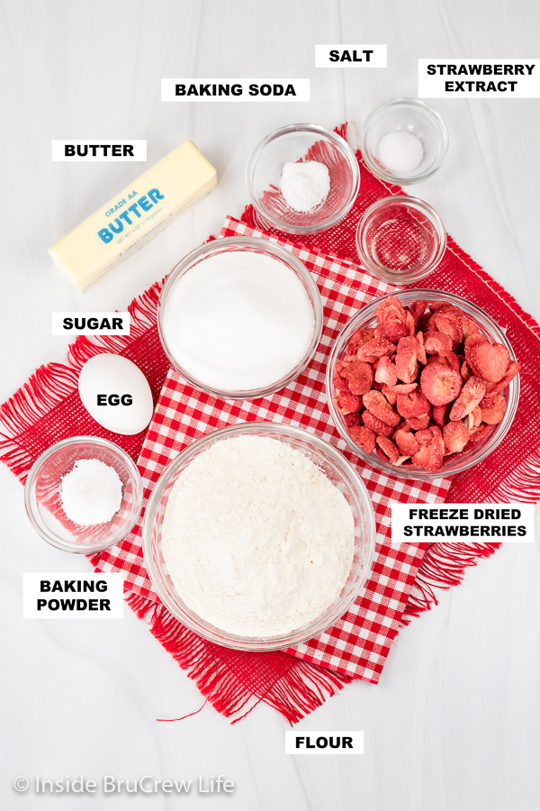 A white board with bowls of ingredients needed to make strawberry sugar cookies.