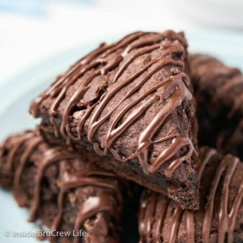 A stack of chocolate drizzled scones on a plate.