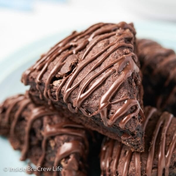 A stack of chocolate drizzled scones on a plate.