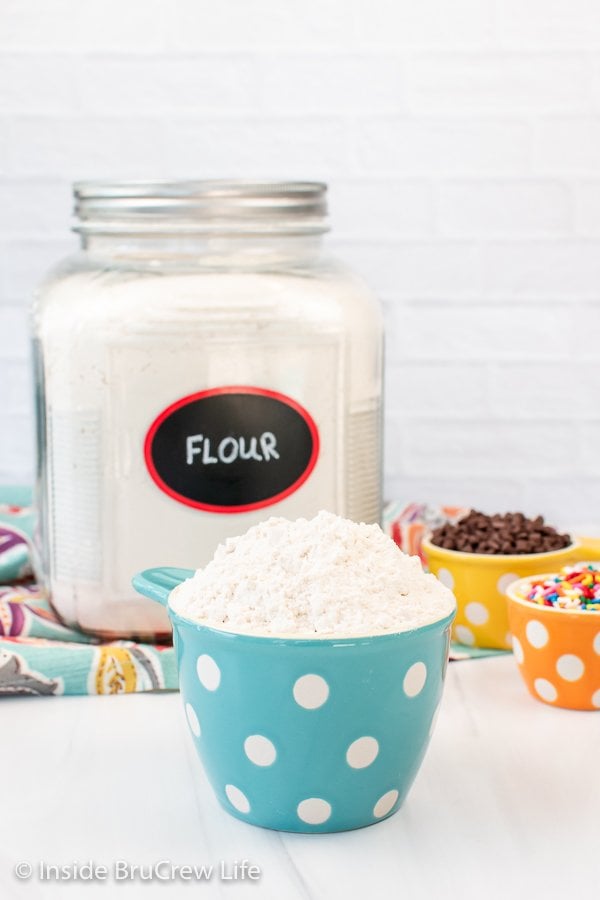 A blue polkadot measuring cup filled with flour.