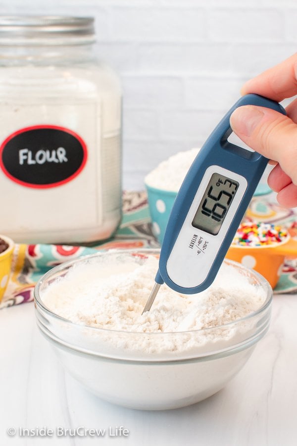 A clear bowl filled with baked flour with a thermometer in it.
