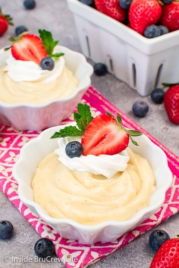 Two white bowls filled with pudding and topped with berries.