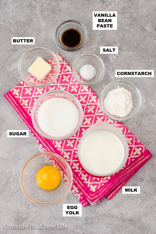 Bowls of ingredients needed to make vanilla pudding on a gray board.