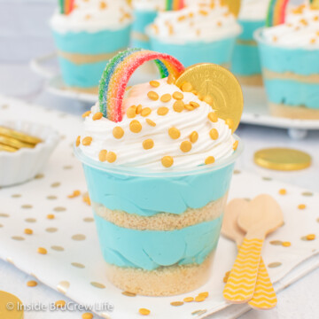 One blue cheesecake cup topped with Cool Whip, rainbow candy, and a gold coin.