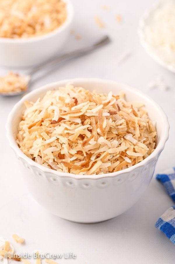 A white bowl filled with toasted coconut.