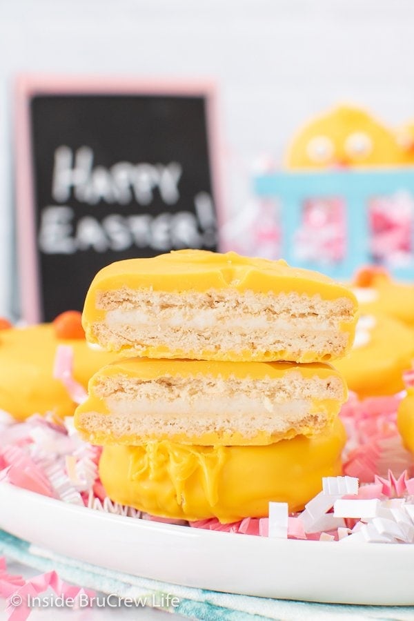 A stack of yellow chocolate covered Oreos on a white plate.