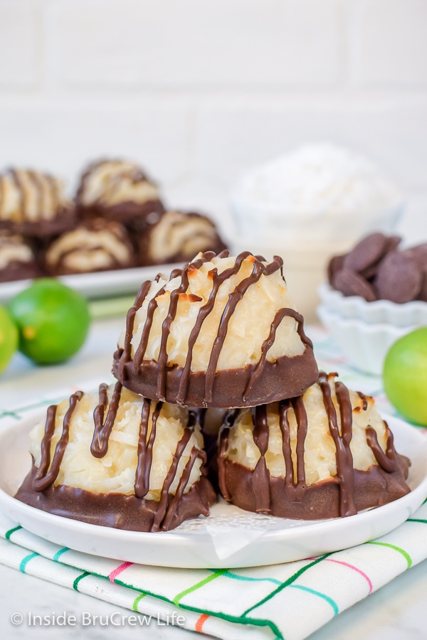 Three chocolate dipped coconut macaroons on a white plate.