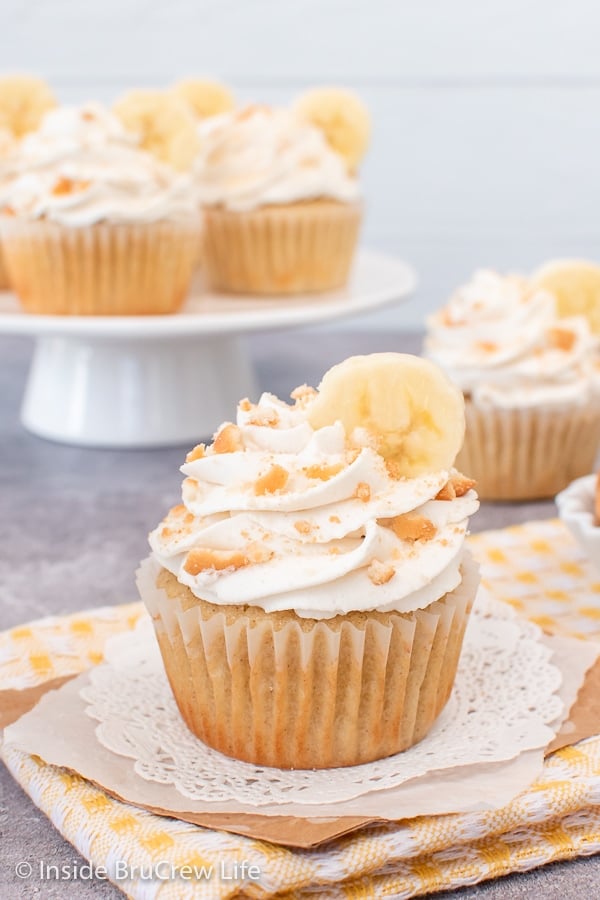 A frosted cupcake topped with a banana slice and crushed cookies.