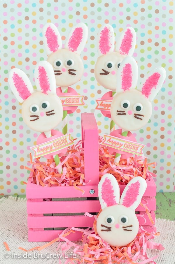 A pink basket with Oreo bunnies on straws stuck in it.