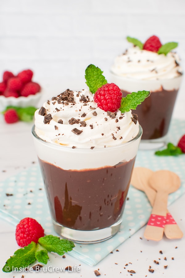 Two chocolate pudding cups topped with whipped cream.