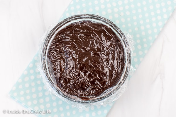 A bowl of chocolate pudding covered with plastic wrap.