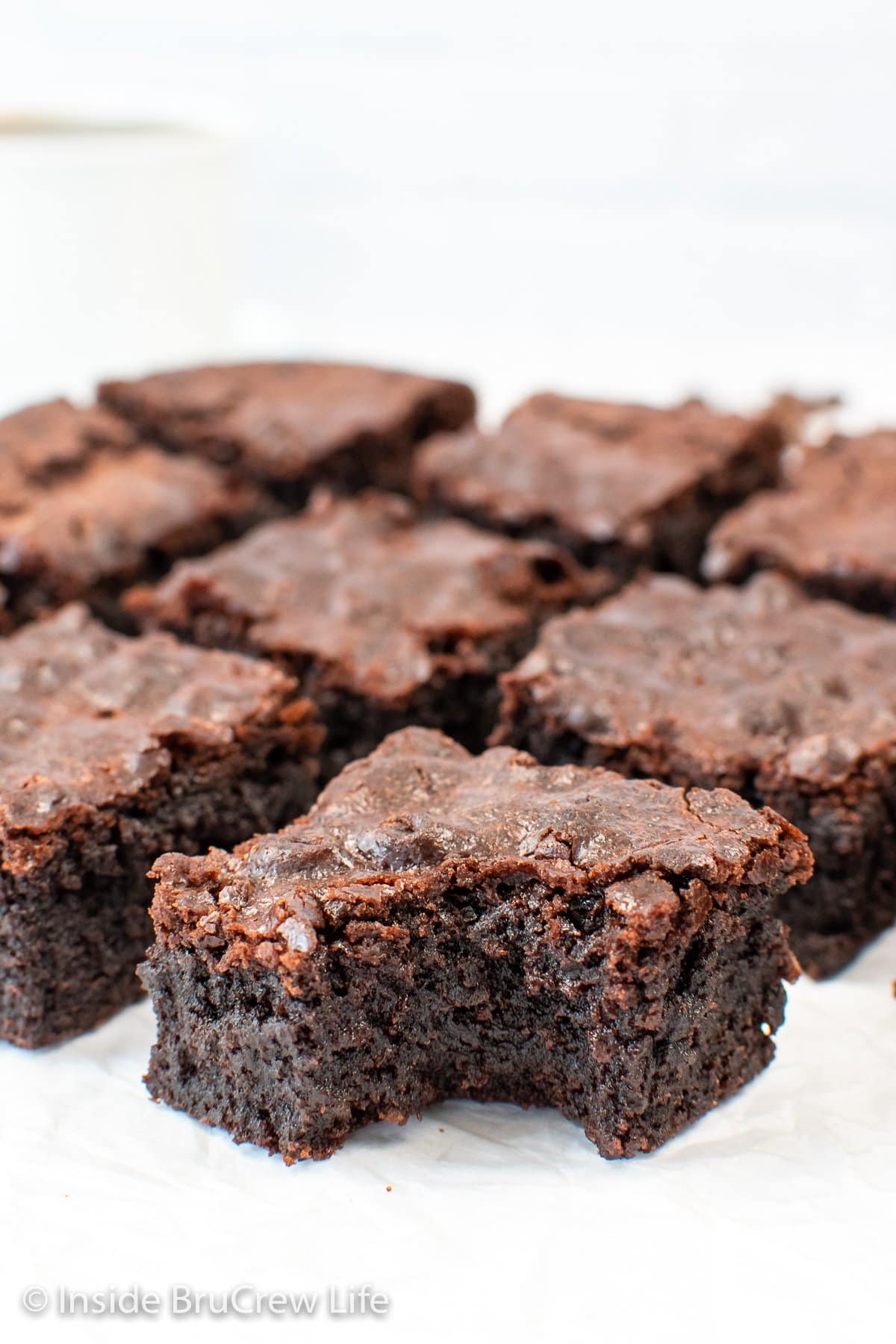 Squares of chocolate brownies sitting on a white background.