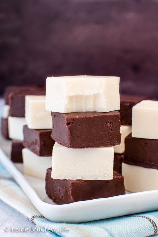 A white plate with squares of chocolate and vanilla fudge stacked on it.