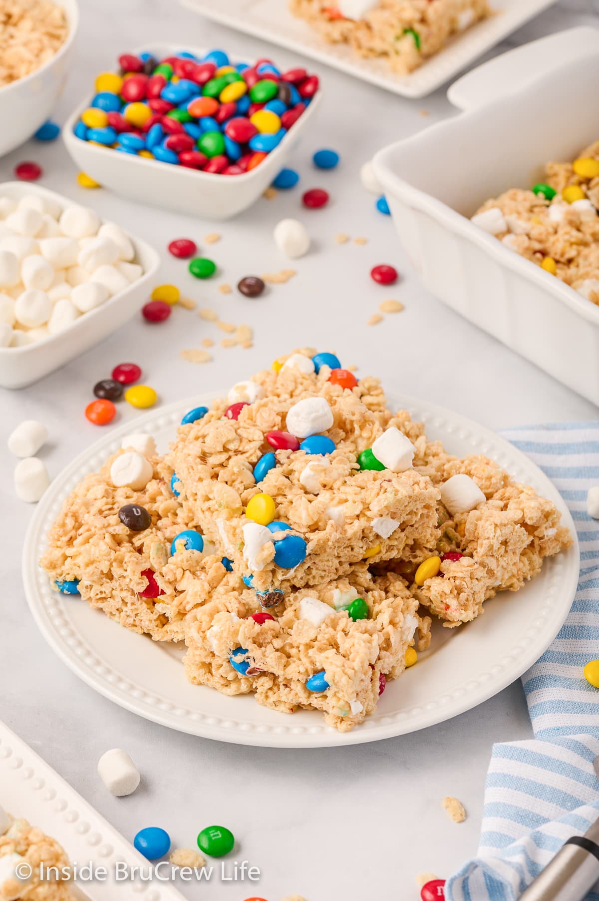 A white plate with squares of rice krispie treats on it.