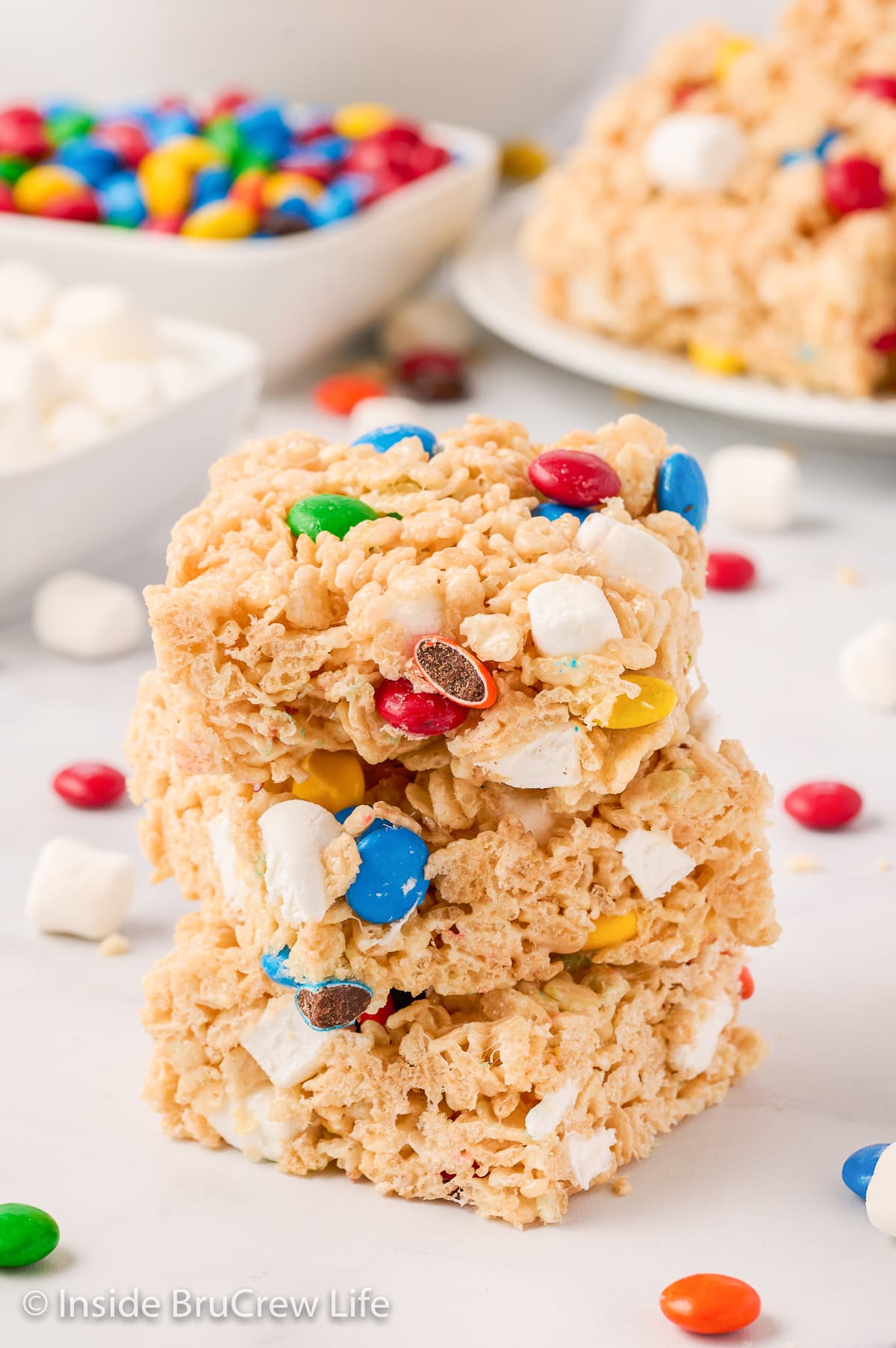 A stack of three rice krispie treat squares on a white board.