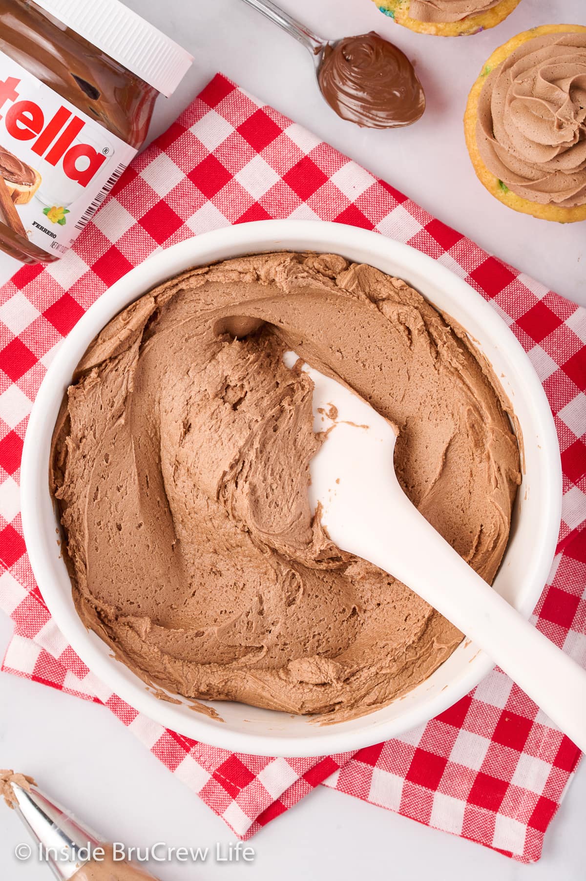 Overhead picture of a white bowl filled with chocolate frosting.