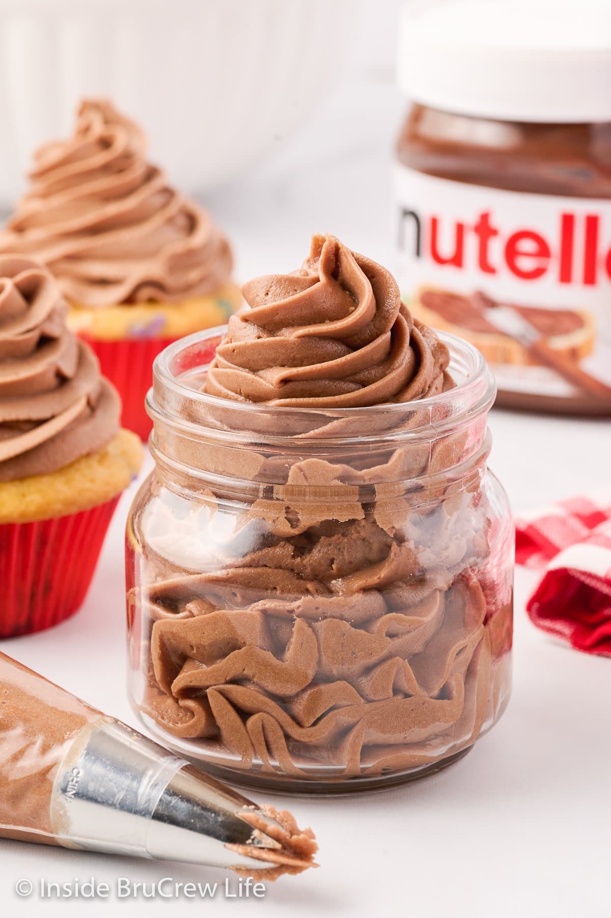 A clear jar filled with a swirl of chocolate Nutella frosting.
