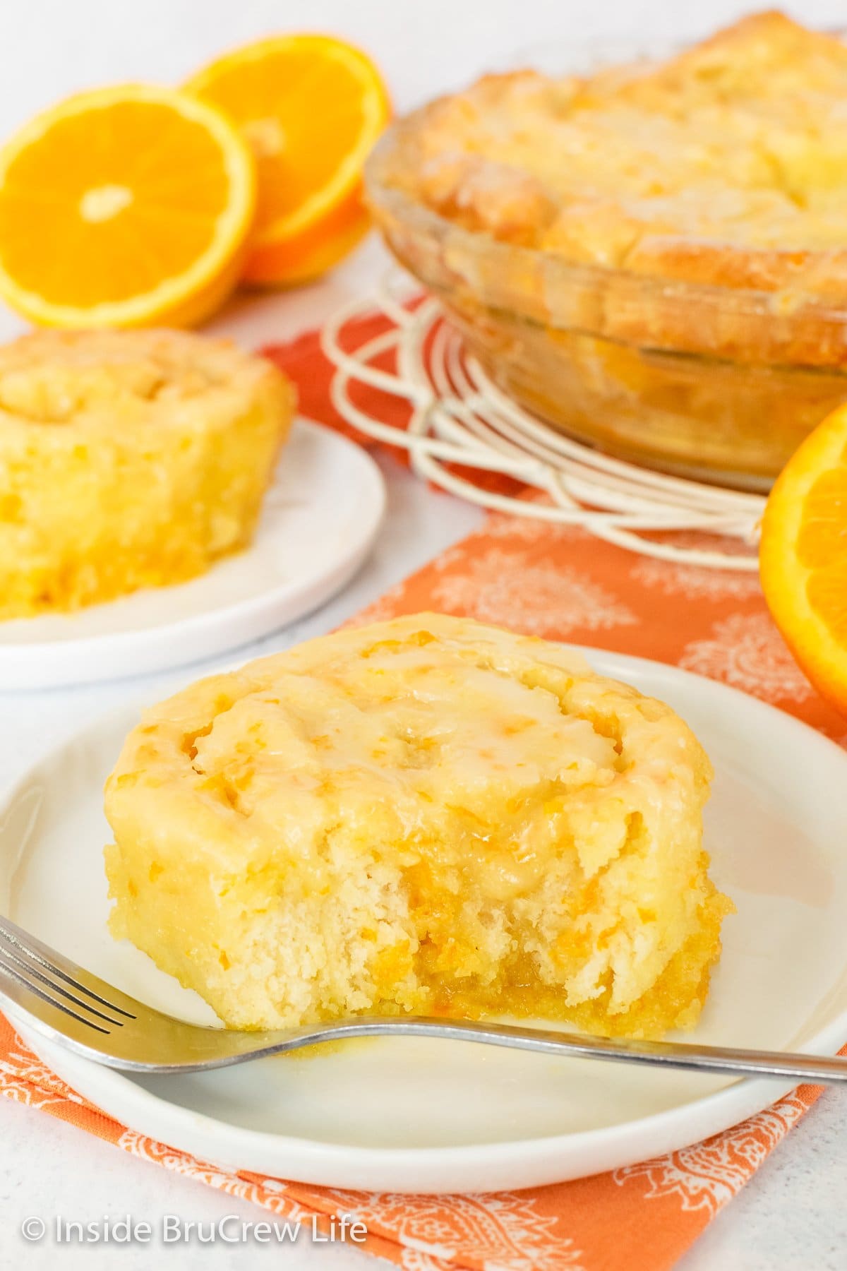 A white plate with an orange roll with a bite out of it.