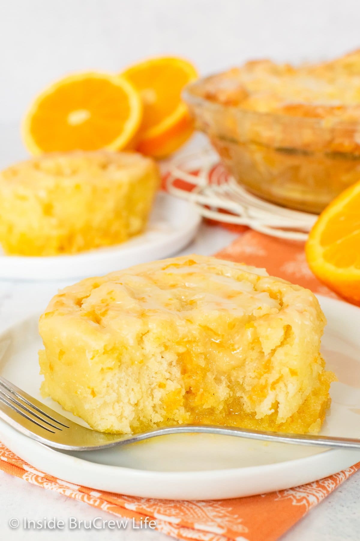 A white plate with an orange roll with a bite out of it.