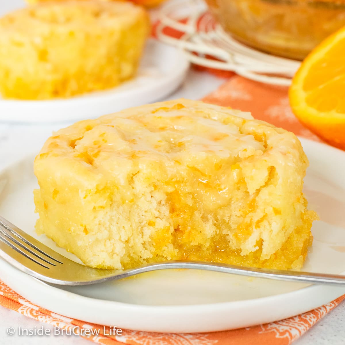 A white plate with an orange roll with a bite out of it.