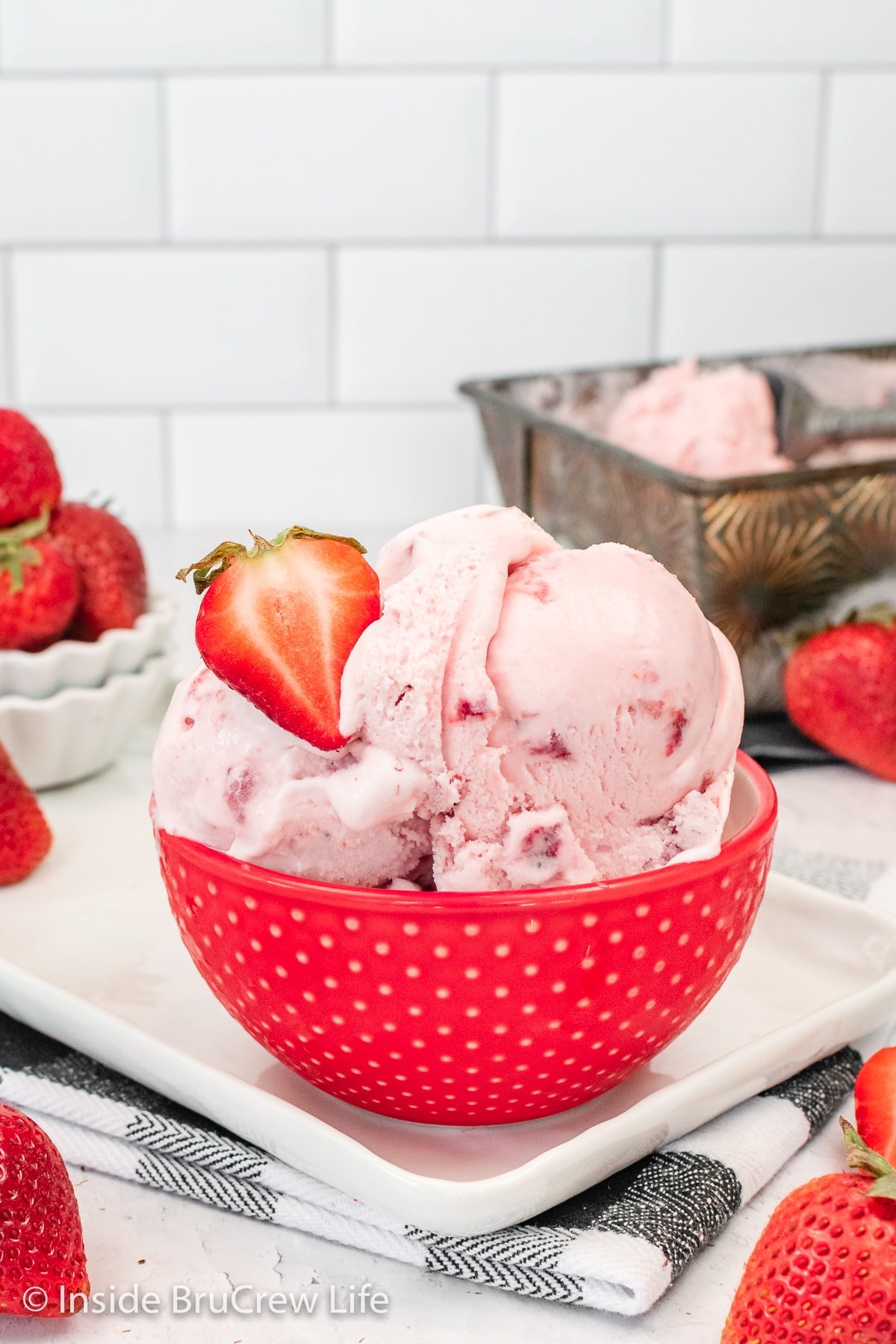 A red bowl with scoops of pink ice cream in it.