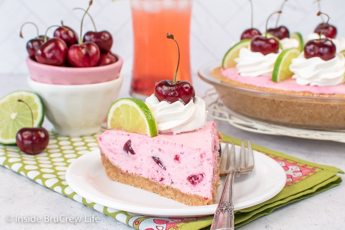A white plate with a slice of pink no bake cherry pie on it.