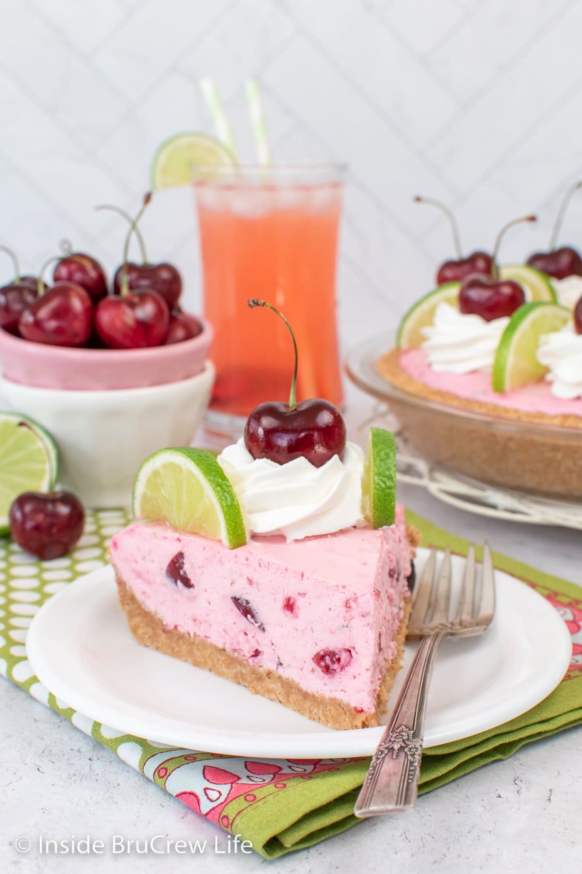 A white plate with a slice of pink no bake cherry pie on it.