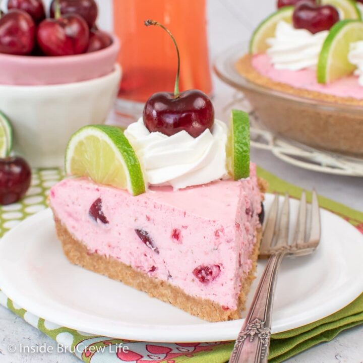 A white plate with a slice of pink no bake cherry pie on it.