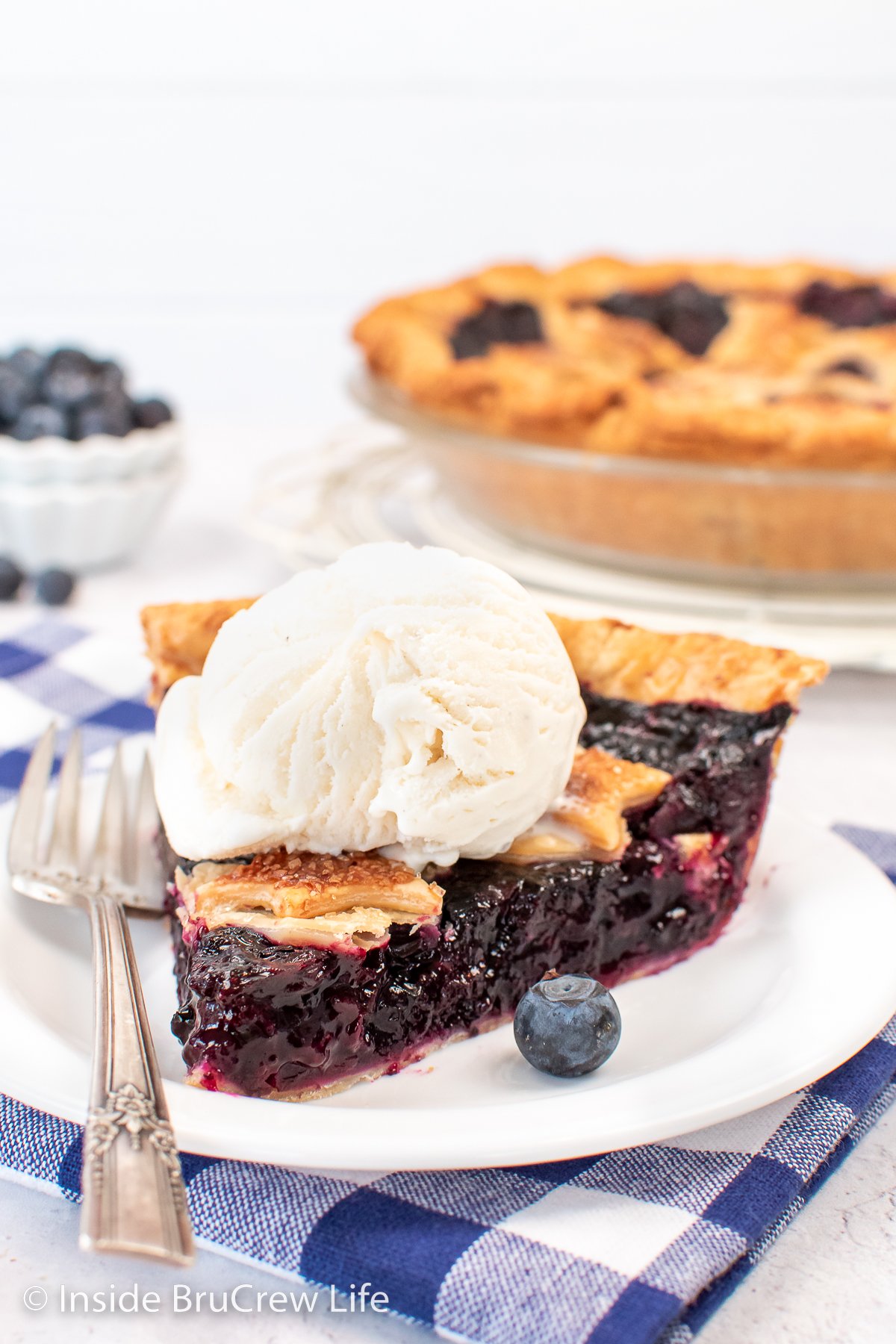 A white plate with a slice of pie and ice cream on it.