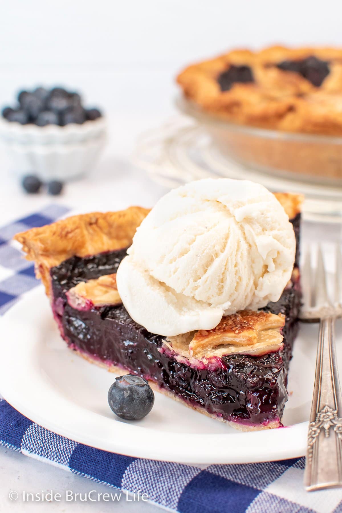 A white plate with a slice of pie and ice cream on it.