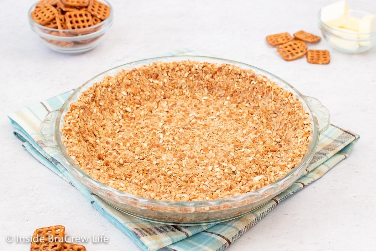 A glass pie plate with a crust in it.