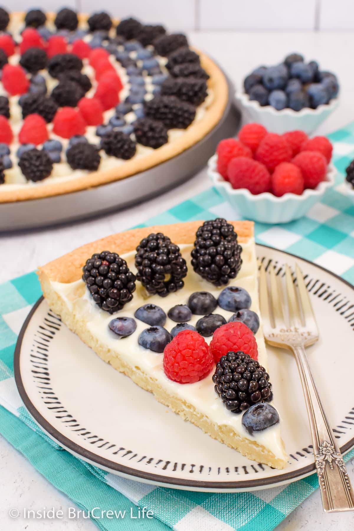A slice of cookie pizza with fruit on a plate.