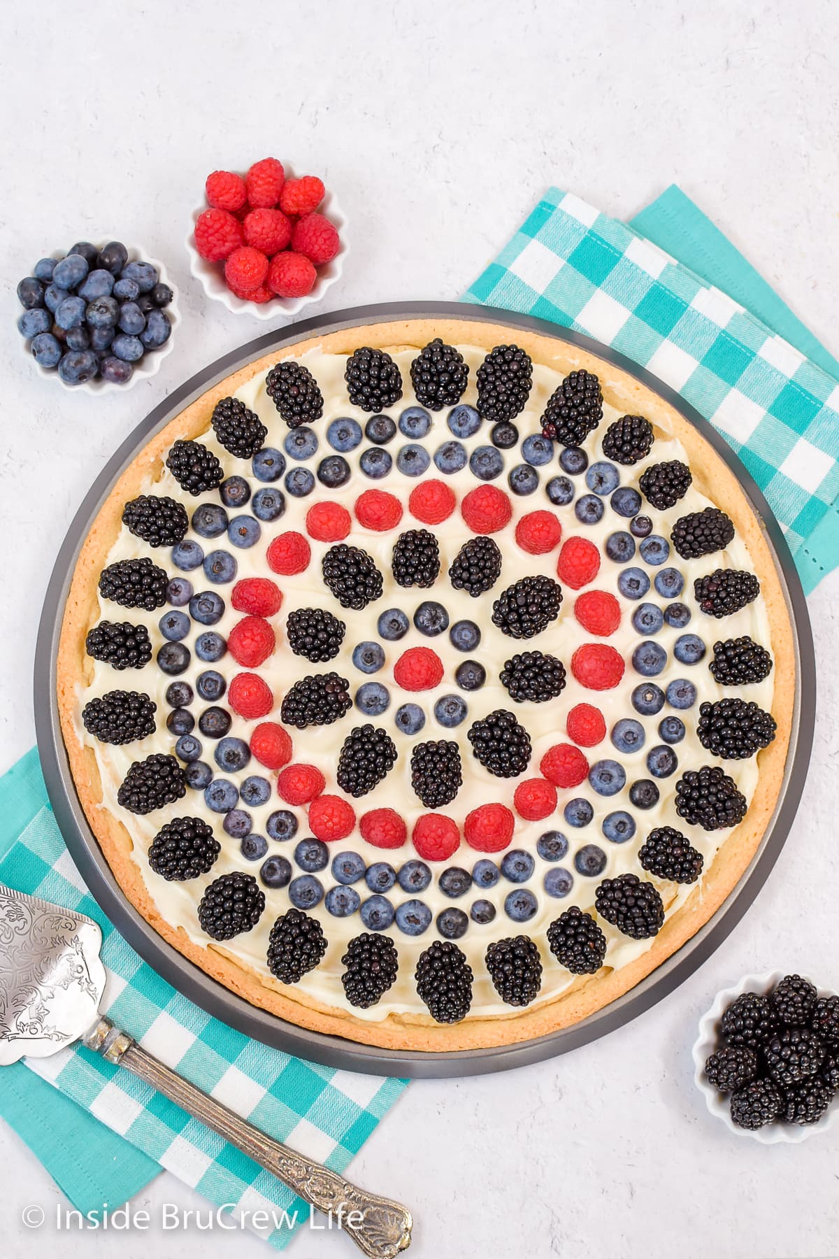 Overhead picture of a fruit pizza on a white board.