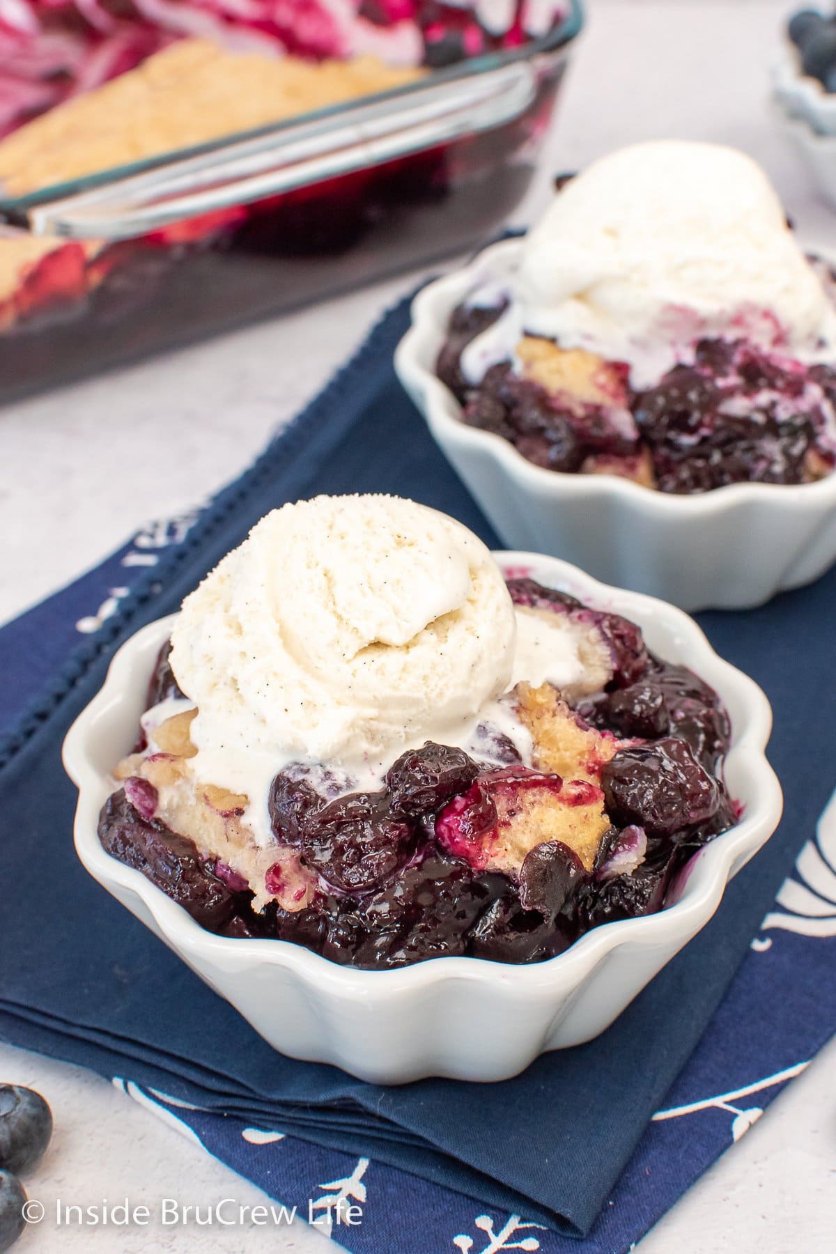 A white bowl of blueberry filling and soft biscuit topping.