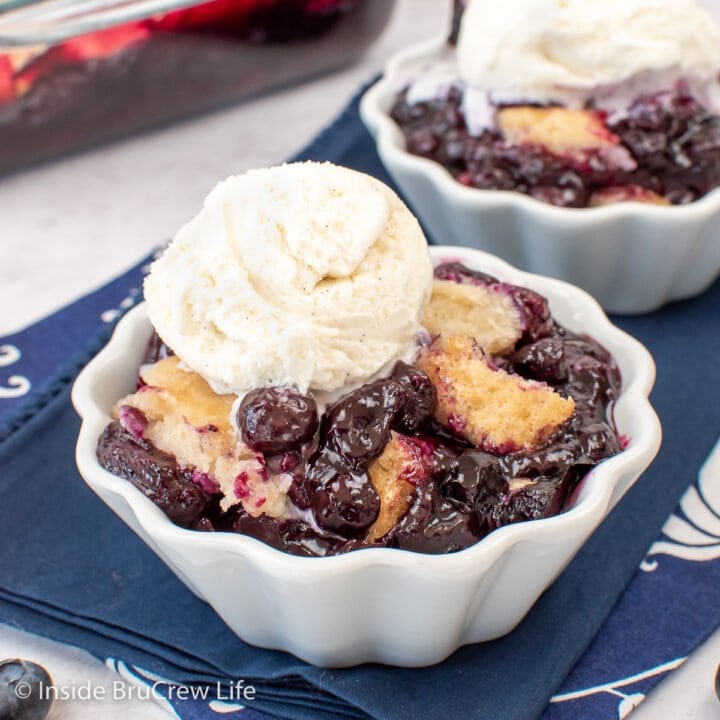Fruit cobbler in a white bowl with vanilla ice cream.