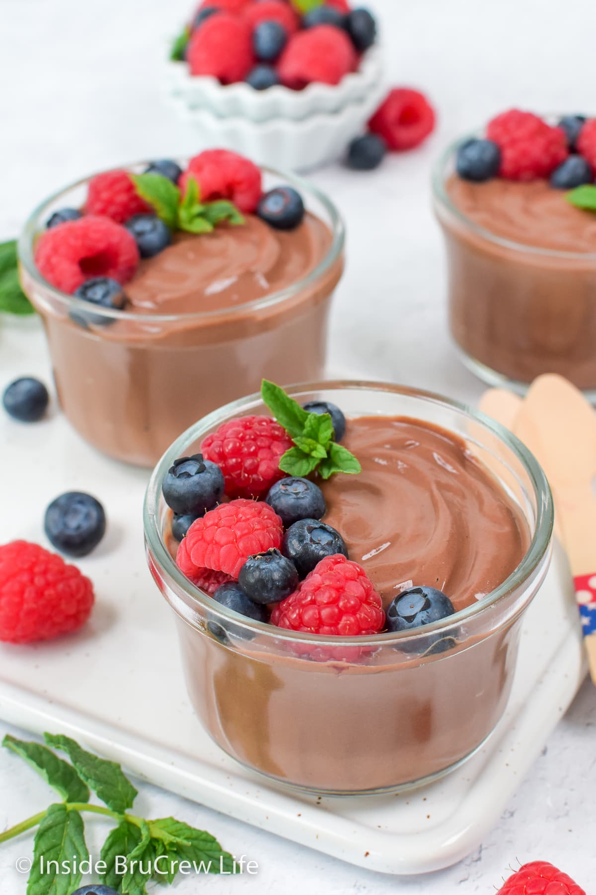 Two bowls of chocolate pudding with berries.