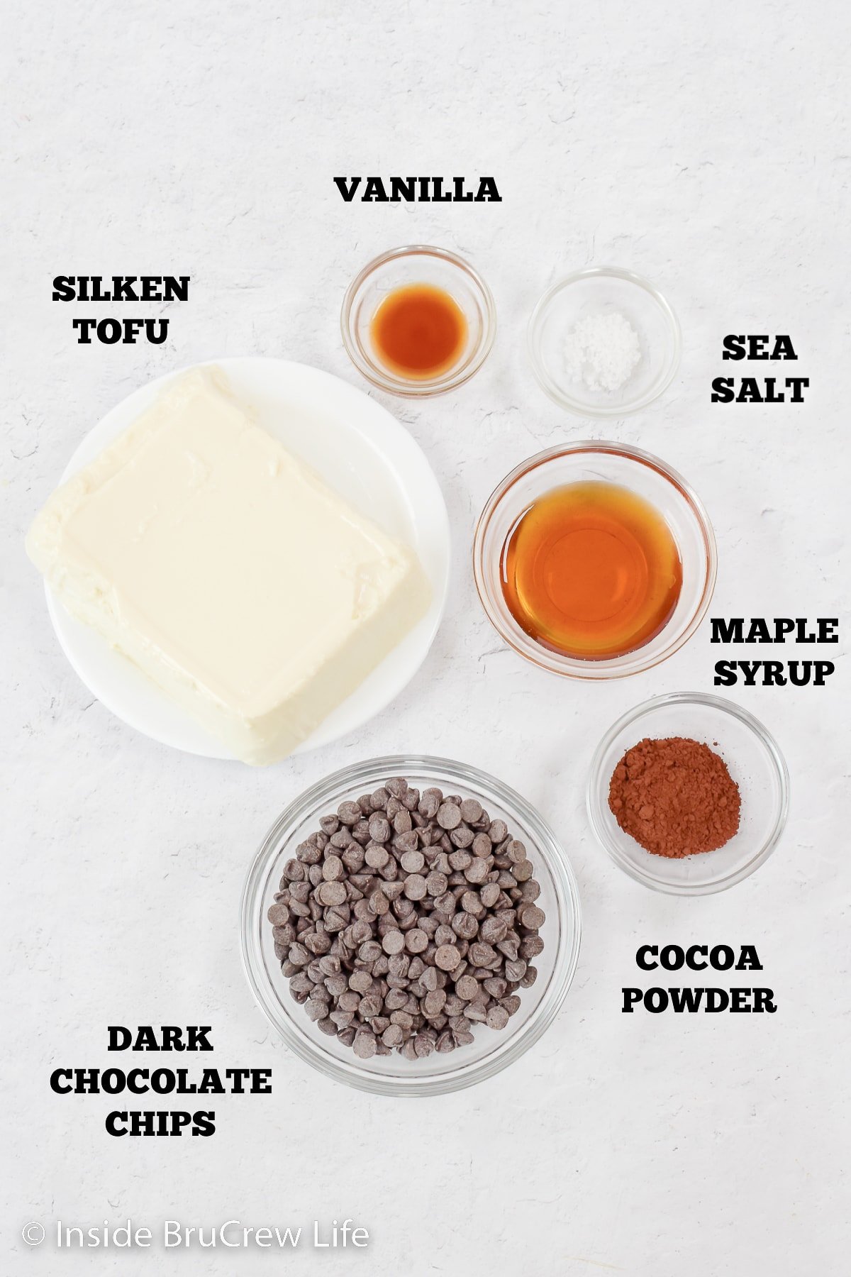 A white board with bowls of ingredients to make vegan pudding.