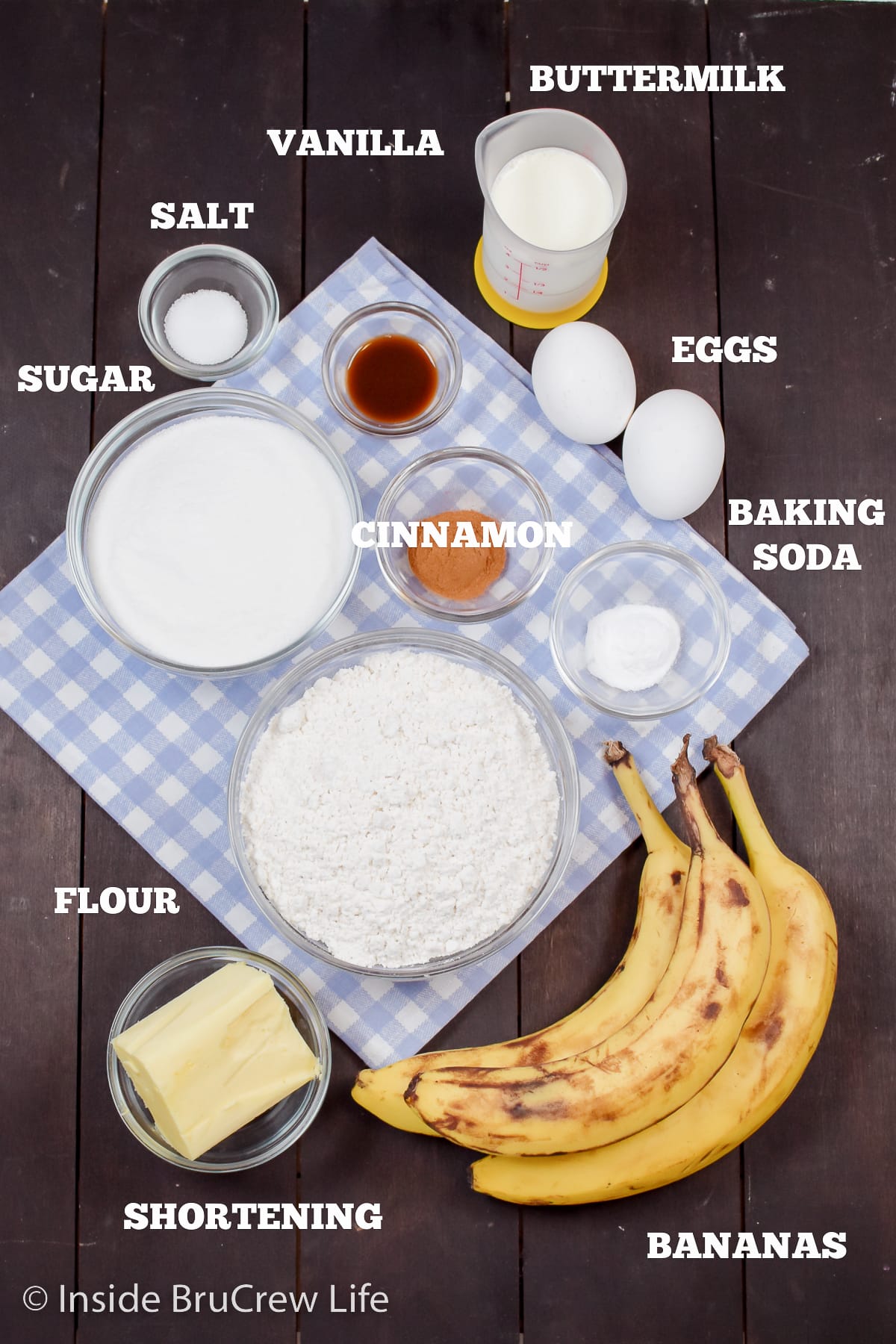 A dark board with bowls of ingredients to make a banana cake.