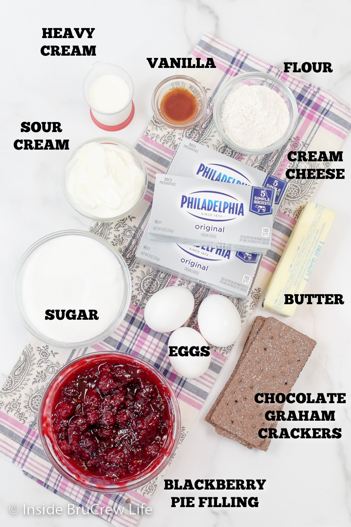 A white board with bowls of ingredients to make a cheesecake.