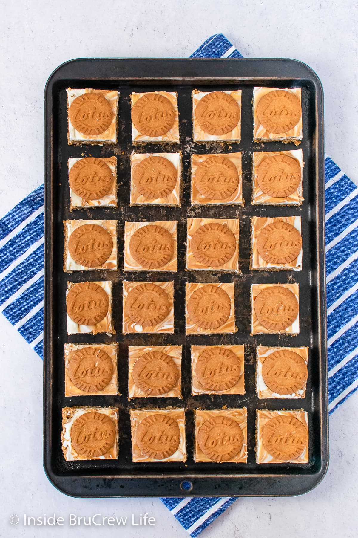 A black tray with oatmeal bars topped with white chocolate and cookies.