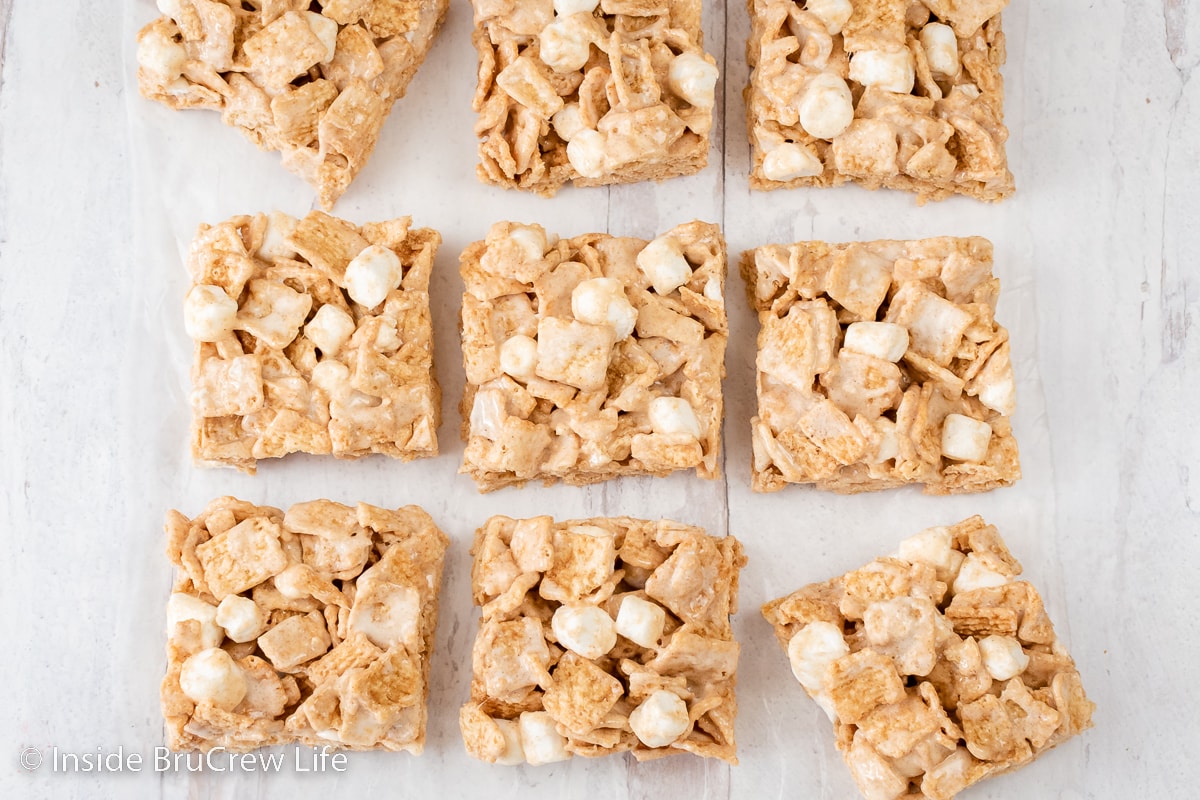 Squares of marshmallow cereal bars lined up on a white board.