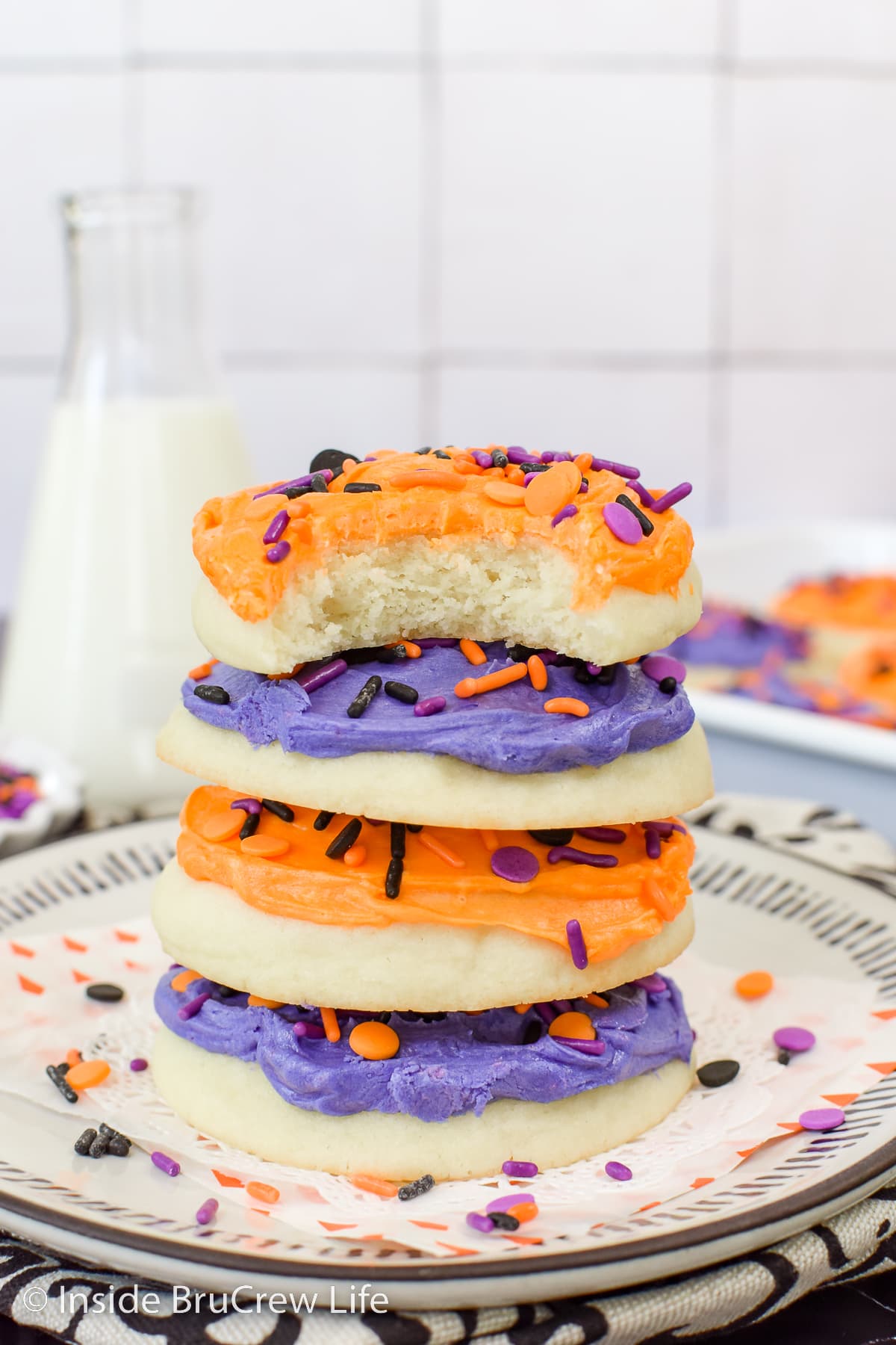 A stack of sugar cookies with frosting on a plate.