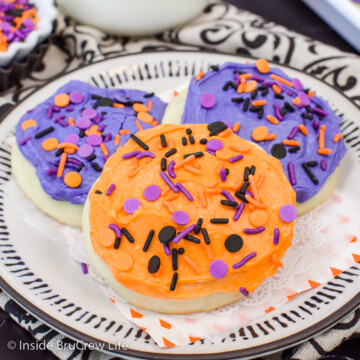 Three frosted cookies with sprinkles on a plate.